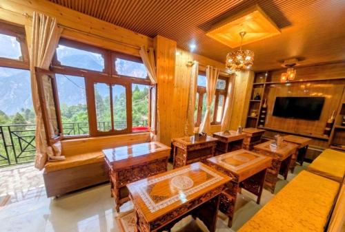 a dining room with tables and a tv and windows at The Kailash Glint in Kalpa