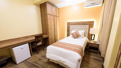 a hotel room with a bed and a desk at Hotel Alles Blau in Pelotas