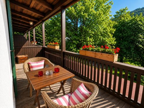 a porch with a wooden table and chairs and flowers at Hotel garni Königslinde - Wandern, Radeln, Skifahren & Genießen in Bayrischzell
