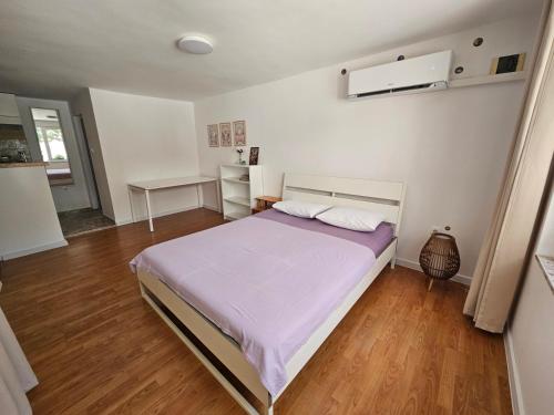 a bedroom with a bed with purple sheets and wooden floors at Studio Garden City Center Pomorie in Pomorie