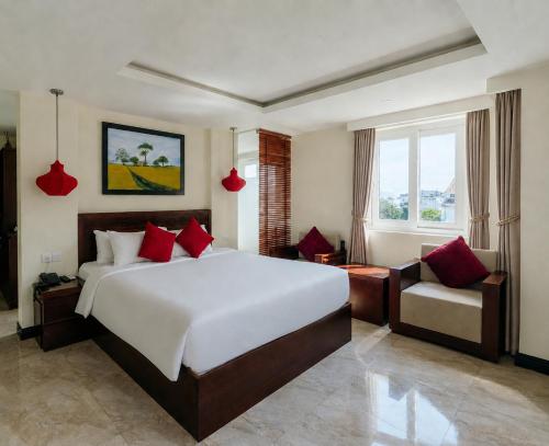 a bedroom with a large white bed and a chair at River Suites Hoi An in Hoi An