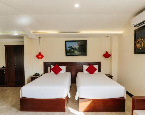 two beds in a hotel room with white and red pillows at River Suites Hoi An in Hoi An