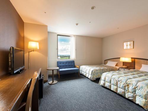 a hotel room with two beds and a tv at Tsubamesanjo Washington Hotel in Sanjo