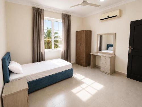a bedroom with a bed and a mirror and a window at Al Shorooq Residential Complex مجمع الشروق السكني in Salalah