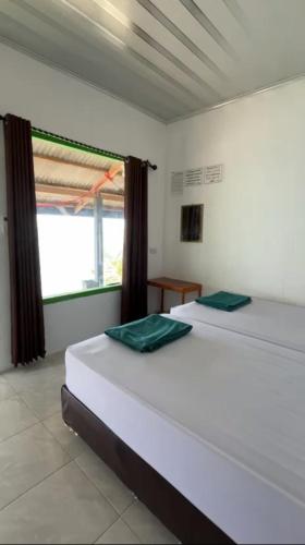 two white beds in a room with a window at AAL Homestay Syariah in Sabang