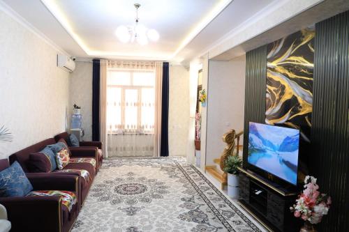 a living room with a couch and a flat screen tv at OSMAN villa in Samarkand
