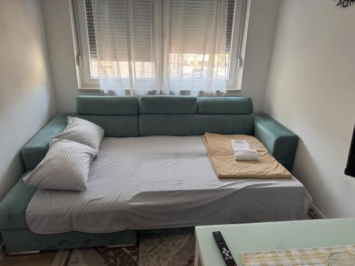 a green couch in a small room with a window at StanČapljina in Čapljina
