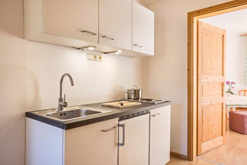 a kitchen with white cabinets and a sink at Bnb Lettnerhof Balcony Family Suite in Monguelfo