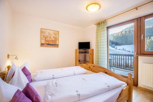 a bedroom with a bed and a large window at Lettnerhof Bnb Family Suite 4 in Monguelfo
