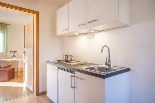 a kitchen with white cabinets and a sink at Lettnerhof Bnb Family Suite 4 in Monguelfo