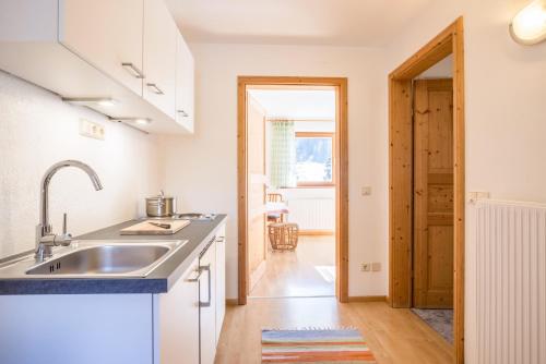 a kitchen with white cabinets and a sink at Lettnerhof bnb Family Suite 3 in Monguelfo