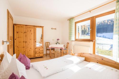 a bedroom with a bed and a table and a window at Lettnerhof bnb Family Suite 3 in Monguelfo