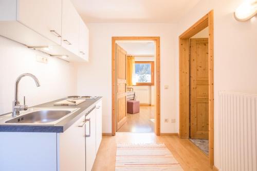 a kitchen with white cabinets and a sink at Lettnerhof bnb Family Suite 2 in Monguelfo