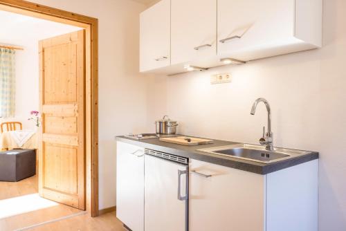 a kitchen with white cabinets and a sink at Bnb Lettnerhof Terrace Family Suite in Monguelfo