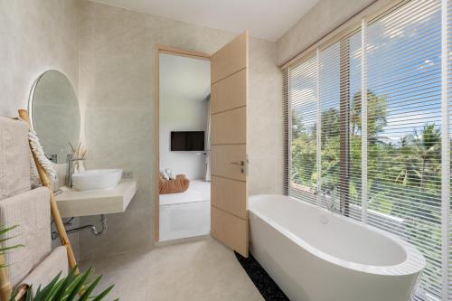 a bathroom with a tub and a sink and a mirror at Modern Jungle Pool Villa in Mae Nam