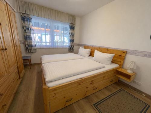 a small bedroom with a wooden bed with white sheets at 10 Ferienwohnung Anders Fewo 1 in Burg auf Fehmarn