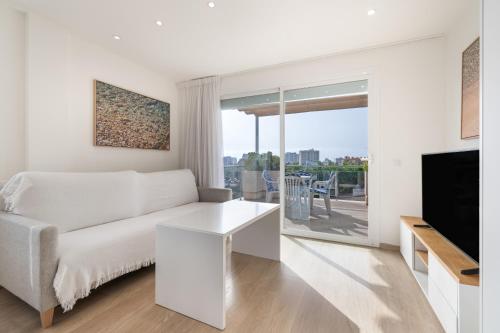 a white living room with a couch and a tv at Apartamento las palmeras 2 Planta 3 in Cala Millor