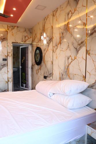 a bedroom with a white bed and a marble wall at Majestic Marvel in Maraiyūr