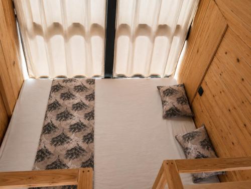 a small bed in a room with a window at MiNi chalet en bois in Menzel Abderhaman