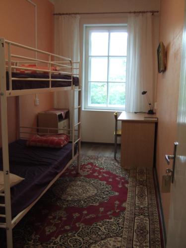 a bedroom with bunk beds and a desk and a window at Kogudusemaja külalistoad in Narva-Jõesuu