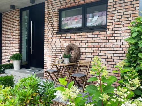 a patio with chairs and a table in front of a brick building at Ferienwohnung HeiDi Lux 1 in Nindorf