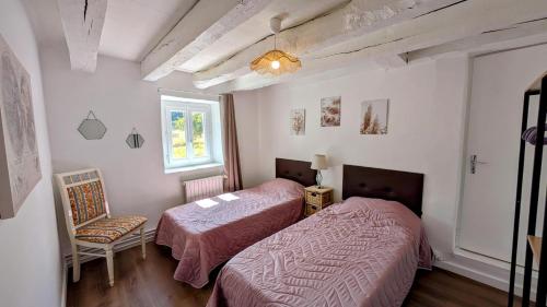 a bedroom with two beds and a chair and a window at Petit villetelle in Cheissoux