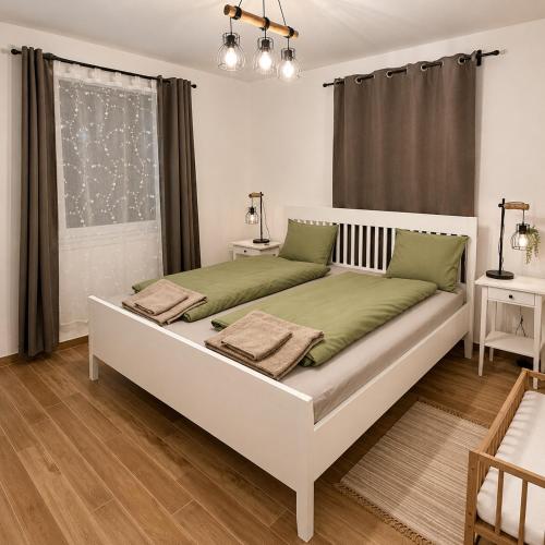 a bedroom with a large white bed with green pillows at A Napos Oldal Vendégház in Abaújkér