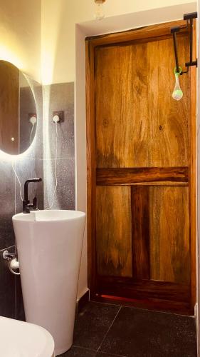 a bathroom with a toilet and a wooden door at Maison Studio indépendante in Nungwi