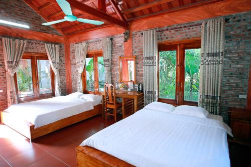 a bedroom with two beds and a desk and windows at Ninh Binh Mountain View Homestay & Restaurant in Ninh Binh