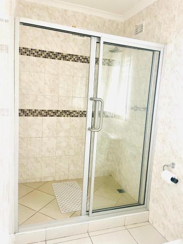 a shower with a glass door in a bathroom at Sky Apartments in Harare