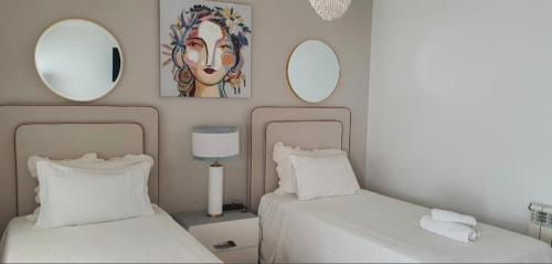 two beds in a bedroom with mirrors on the wall at Vivenda Valverde in Nazaré