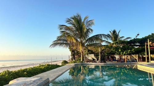 a swimming pool next to a beach with palm trees at Lõst Soles Lodge in Jambiani