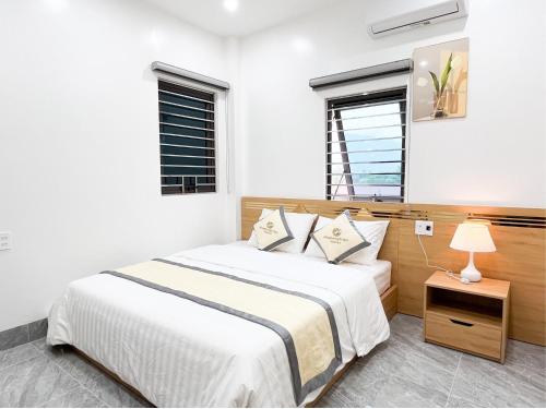 a white bedroom with a bed and a lamp at HagiangTrips Hotel in Ha Giang