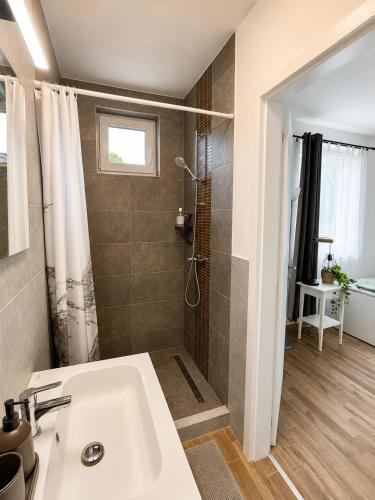a bathroom with a white sink and a shower at A Napos Oldal Vendégház in Abaújkér