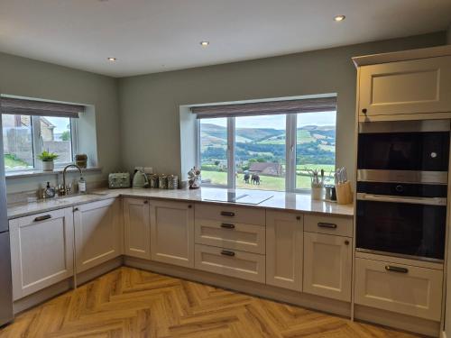 a large kitchen with white cabinets and a large window at Thorn Tree Cottage in Hope