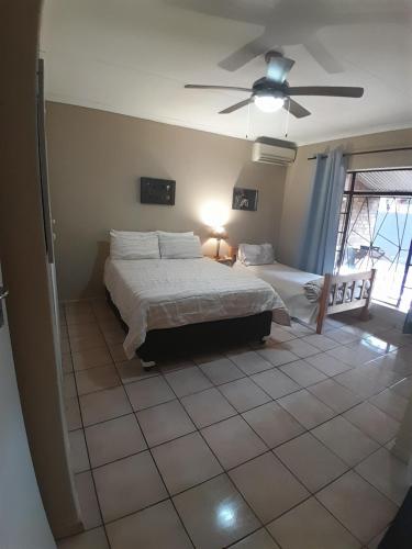 a bedroom with two beds and a ceiling fan at Ligema Lodge in Malelane