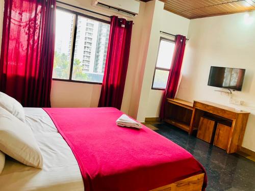 a bedroom with a bed with red curtains and a tv at Oval Retreat in Cochin