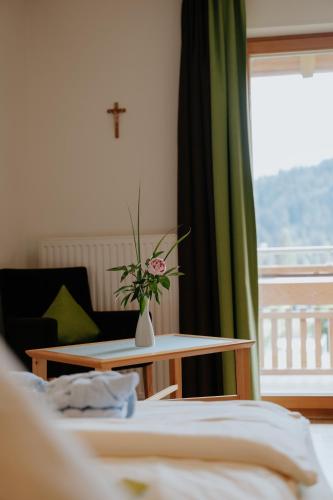 a room with a table with a vase with a flower on it at Almhof Lässer in Balderschwang
