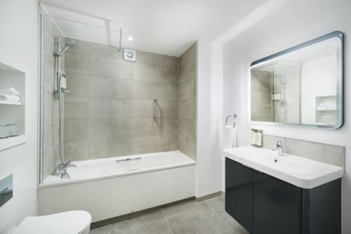 a bathroom with a tub and a sink and a mirror at voco St. Johns Solihull by IHG in Solihull