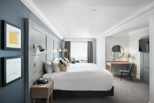 a hotel room with a large white bed and a desk at voco St. Johns Solihull by IHG in Solihull
