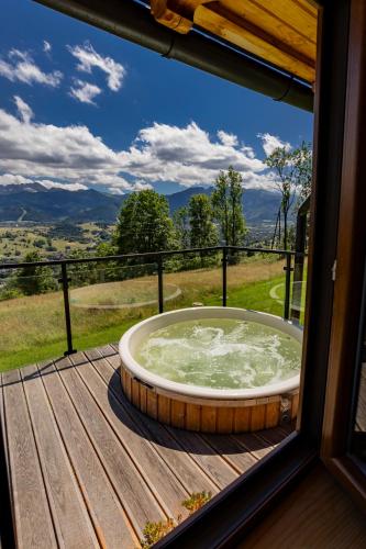 a hot tub sitting on a deck with a window at Domki Widokowe Wooden Pod Gubałówką z Jacuzzi in Ząb
