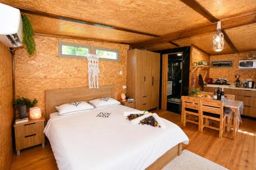 a bedroom with a white bed and a kitchen at השקט של כליל - בקתה קסומה בטבע עם בריכה פרטית in Clil
