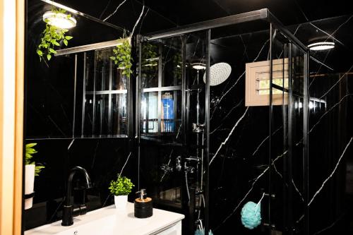 a black bathroom with a sink and a shower at השקט של כליל - בקתה קסומה בטבע עם בריכה פרטית in Clil