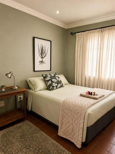 a bedroom with two beds and a table and a window at Tree Aloe Guest House in Mokopane