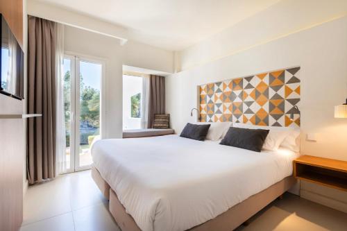 a bedroom with a large white bed and a window at Inturotel Esmeralda Villas in Cala d´Or