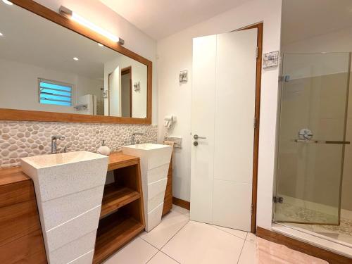 a bathroom with two sinks and a mirror and a shower at Beachfront Penthouse - Panoramic Ocean View in Cap Malheureux