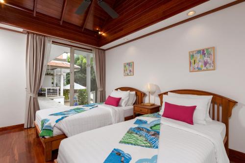 two beds in a room with a window at Katamanda B2 Tropical Pool Villa Kata Beach in Kata Beach