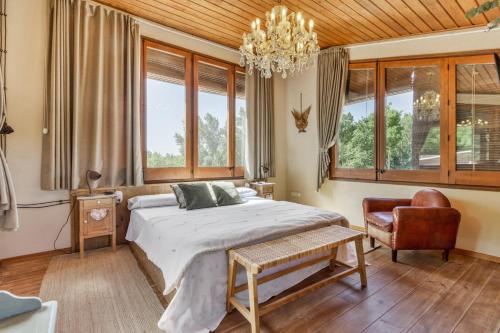 a bedroom with a bed and a chair and windows at Nuestro Antiguo Pajar in Solsona