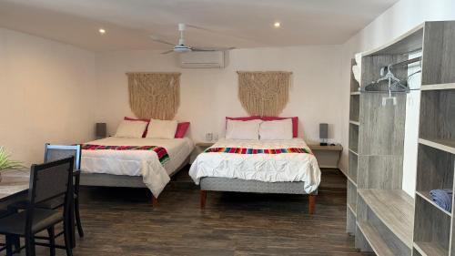two beds in a room with a table and chairs at Sol de México in Isla Mujeres