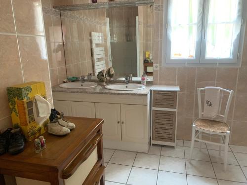 a bathroom with two sinks and a mirror and a chair at Le temps d une escapade vendéenne in Saint-Gervais